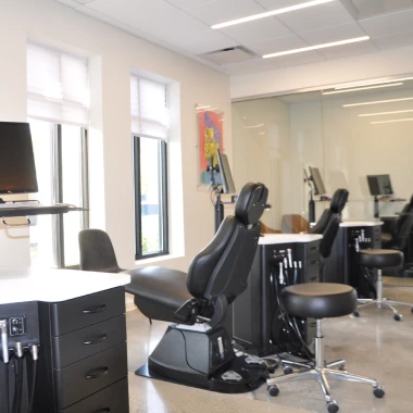 Treatment area at Pappas Orthodontics showing dental chairs, equipment, monitors, and large windows.