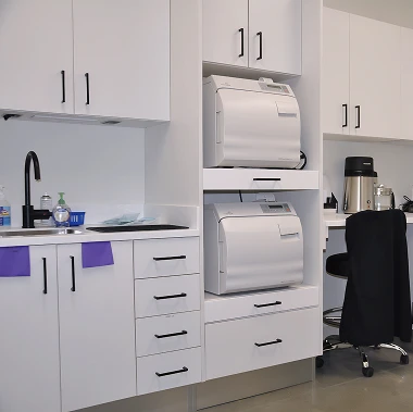 Sterilization room at Pappas Orthodontics featuring white cabinetry, dental equipment, and workspace.